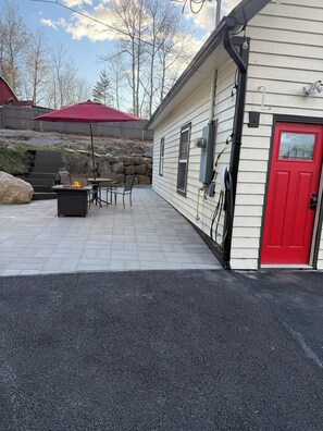 A house with a red door, outdoor seating, and a stone wall.