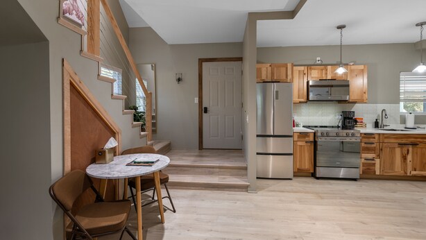 A modern kitchen with wooden cabinets, stainless steel appliances, and a marble dining table. - Cozy Modern Home  (Lake Placid)