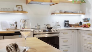Et moderne køkken med træskabe, stålemmer og et glas hvidvin på bordpladen.