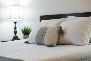 Ein ordentlich bezogenes Bett mit weißer Bettwäsche und einem dekorativen Kissen.