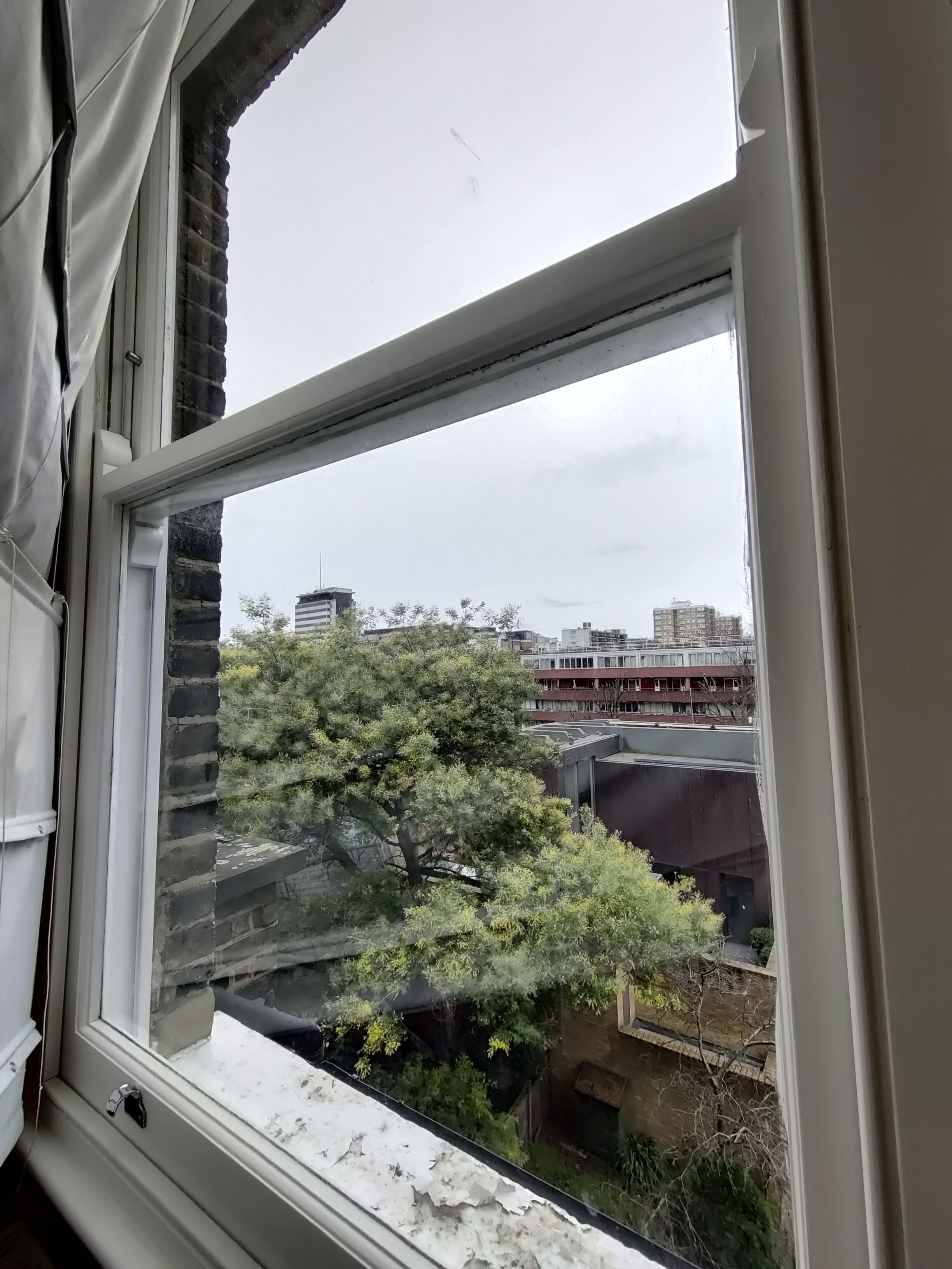 A window with a view of a building and trees.