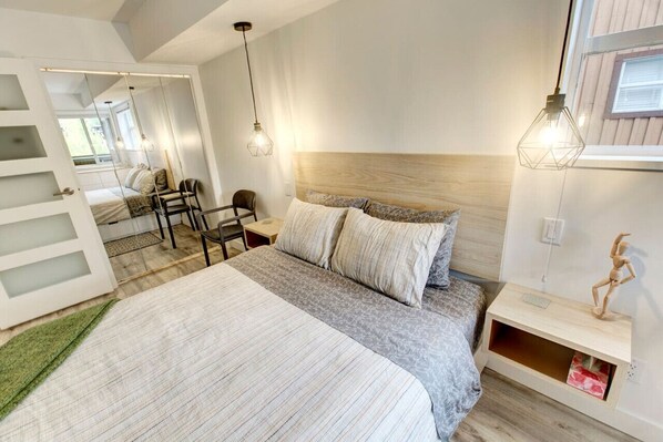 A modern bedroom with a large bed, a wooden headboard, and a small wooden nightstand.