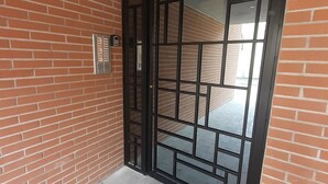 Un mur extérieur en briques, agrémenté d’un portail métallique et d’une caméra de surveillance.