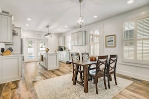 Una cocina amplia con muebles blancos, una zona de comedor con sillas de madera y una isla grande.