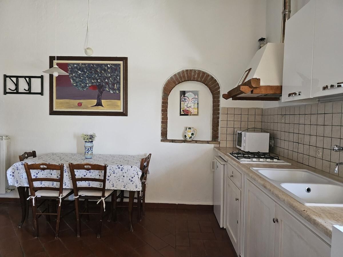 A kitchen with a dining table, chairs, a microwave, a stove, and a sink.