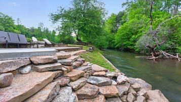 Une terrasse au bord de la rivière, agrémentée d’escaliers en pierre, de sièges extérieurs et d’une végétation luxuriante.