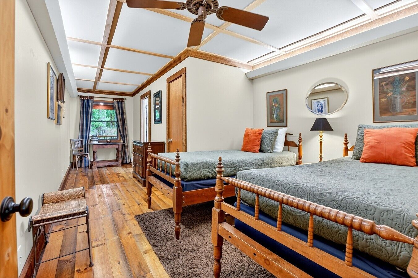 A bedroom with two wooden beds, a ceiling fan, and a view of the outdoors.