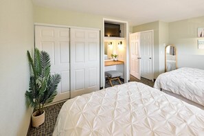 A hotel room with two beds, a desk with a chair, a television, and a large mirror.