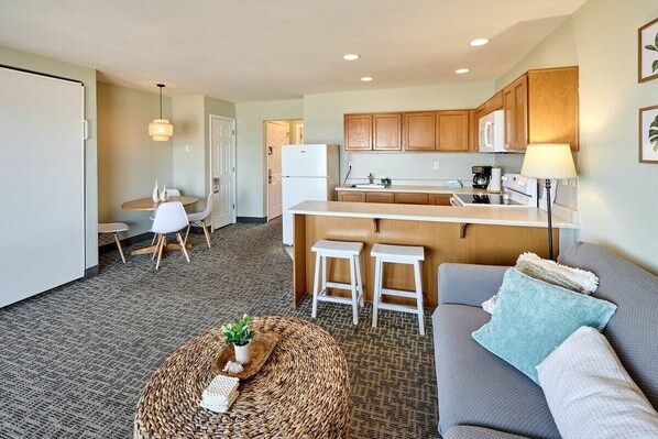 A compact living space with a kitchenette, a dining area, and a seating area with a sofa and ottoman.