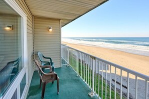 A balcony with a view of the beach, a chair, and a small table. - Ocean View Suite - Beach And Pool Access! (Lincoln City)
