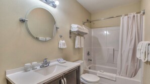 Ein Badezimmer mit Waschbecken, Spiegel, Toilette und Duschbereich.