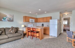 A compact living space with a kitchenette, a sofa, a dining area, and a small bedroom. - Beachfront Family Suite - Ocean View - Full Kitchen (Lincoln City)