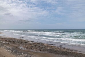A beach with waves, a clear sky, and rocky terrain. - Beachfront Suite with Ocean View, Full Kitchen, Pool & Hot Tub Access! (Lincoln City)