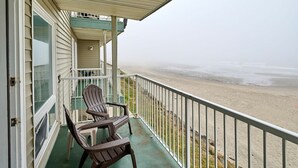 En balkong med två Adirondack-stolar med utsikt över en strand.