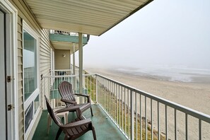 Ein Balkon mit zwei Adirondack-Stühlen mit Blick auf einen Strand.
