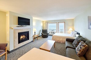 A hotel room with a fireplace, a television, a bed, a sofa, and a view of the sea. - Stunning Oceanfront Suite - Full Kitchen - Heated Indoor Pool & Hot Tub! (Lincoln City)