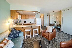 Un espacio habitable compacto con kitchenette, sofá, mesa de centro y comedor.