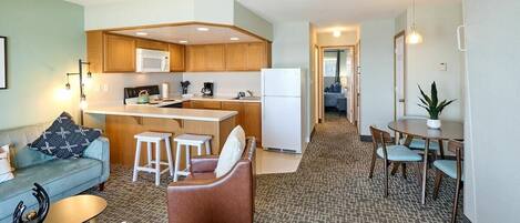 A compact living space with a kitchenette, a dining area, and a seating area with a sofa and chairs.