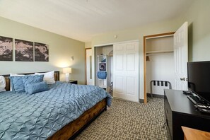 A hotel room with a bed, a desk, a television, and a wardrobe.