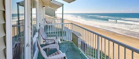 A balcony with a view of the beach and ocean.