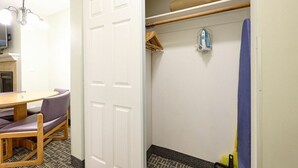 Una habitación con una mesa de comedor y sillas, una puerta blanca, una zona de ducha con un tapete azul y un perchero.