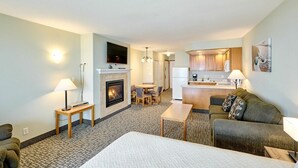 Habitación de hotel con chimenea, sofá, mesa de comedor y zona de cocina.