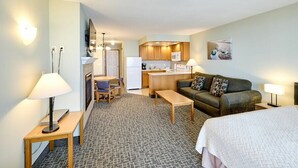 Una habitación de hotel con kitchenette, un sofá, una cama y una pequeña mesa de comedor.
