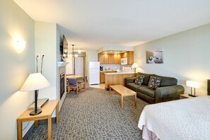 A hotel room with a kitchenette, a sofa, a bed, and a small dining table. - Top Floor Family Suite with Fireplace and Kitchen - Beach Access - Beautiful Ocean Views! (Lincoln City)