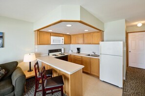 Una cocina compacta con gabinetes de madera, microondas, estufa y refrigerador.