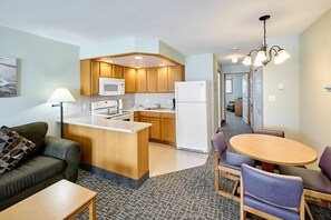 Een knus woongedeelte met een kitchenette, een eethoek en een bank.