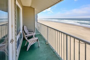 Een balkon met uitzicht op het strand, een stoel en een hekwerk.