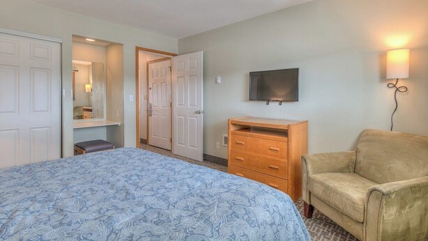 Un dormitorio con cama, cómoda, televisor y lámpara.
