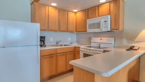 Una cocina con armarios de madera, un refrigerador blanco, un microondas y una estufa.