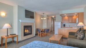 Habitación de hotel con chimenea, comedor, kitchenette y sala de estar con sofá y alfombra estampada.