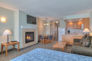 A hotel room with a fireplace, a dining area, a kitchenette, and a living room with a sofa and a patterned rug. - Stunning Oceanfront Suite - Sleeps Six - Top Floor - Heated Pool & Hot Tub Access! (Lincoln City)
