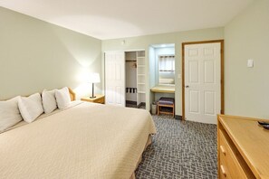Une chambre d’hôtel comprenant un lit, un bureau, une chaise, une armoire et un petit coin salon.