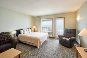 A hotel room with a bed, a chair, a sofa, a table, and a balcony with a view.