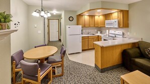 A compact kitchen with a refrigerator, microwave, and stove. There is a dining area with a table and chairs. - Stunning Top Floor Corner Suite for 6! Beautiful Ocean Views & Easy Beach Access! (Lincoln City)