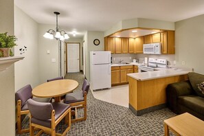 A compact kitchen with a refrigerator, microwave, and stove. There is a dining area with a table and chairs. - Stunning Top Floor Corner Suite for 6! Beautiful Ocean Views & Easy Beach Access! (Lincoln City)