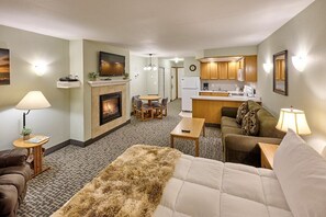 Habitación de hotel con chimenea, sofá, comedor y cocina.