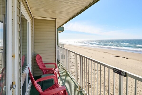 A beach view from a porch with red chairs and a railing. - Amazing Ocean View Suite - Sleeps Six - Pool Access & Hot Tub! (Lincoln City)