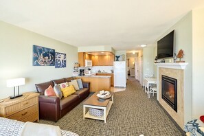 A hotel room with a living area, kitchenette, and a fireplace.