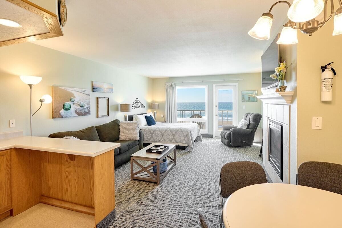 A hotel room with a bed, a sofa, a dining table, and a fireplace.