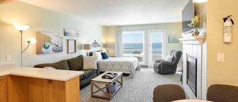 A hotel room with a bed, a sofa, a dining table, and a fireplace.