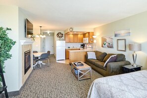 Un espacio habitable compacto con kitchenette, comedor, sofá y cama.