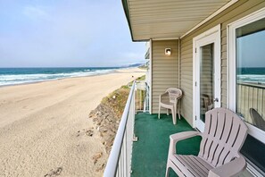 A beachfront property with a covered porch, a chair, and a view of the ocean. - Fireplace Suite With King Bed, Full Kitchen, Ocean Views - Heated Indoor Pool and Hot Tub! (Lincoln City)