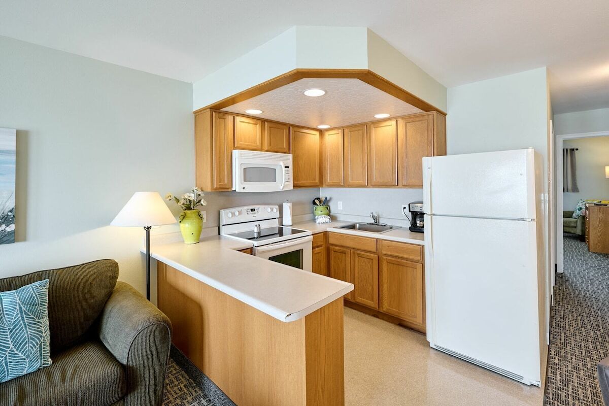 Cocina compacta con armarios de madera, microondas, estufa y refrigerador.
