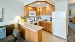 A compact kitchen with wooden cabinets, a microwave, stove, and refrigerator.