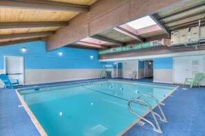 Une piscine intérieure avec des couloirs bien délimités, un plongeoir et un plafond doté de lucarnes.