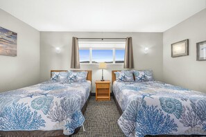 Une chambre d’hôtel avec deux lits, une fenêtre avec des rideaux, une table de chevet avec une lampe et un sol recouvert de moquette.